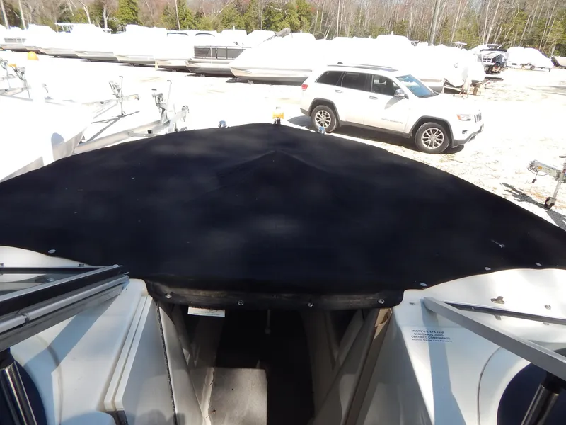 Slide: The Image of 2013 Bayliner 235 Bowrider with black cover in a boatyard. - 28