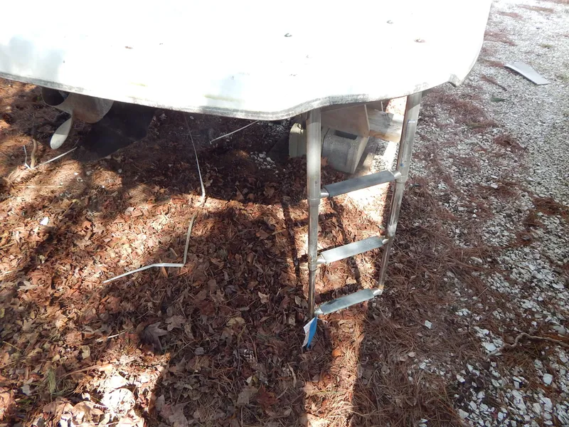 Slide: The Image of 2013 Bayliner 235 Bowrider boat with ladder on dry leaves and gravel. - 7