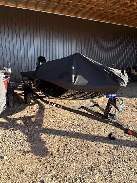 Slide: The Image of 2025 Lowe Skorpion 17 boat covered, parked on a trailer in a garage. - 5