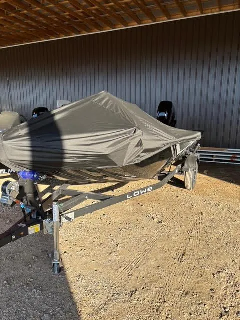 Slide: The Image of 2025 Lowe Skorpion 17 boat covered, parked on a trailer in a shaded area. - 6