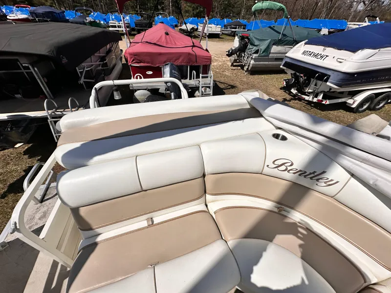 Slide: The Image of 2006 Bentley Pontoons 240 Cruise Pontoon with beige seating, parked among other boats. - 10