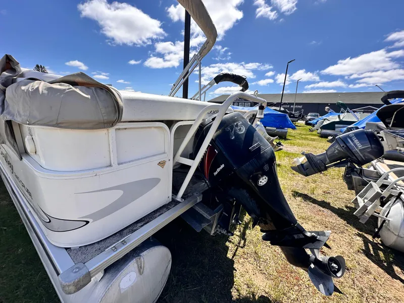 Slide: The Image of 2006 Bentley Pontoons 240 Cruise Pontoon with outboard motor, parked outdoors under blue sky. - 11