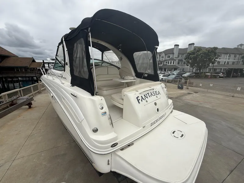 Slide: The Image of 2004 Sea Ray 300 Sundancer boat docked, featuring a black canopy and white exterior. - 10