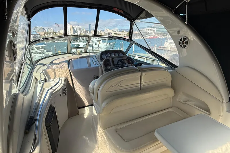 Slide: The Image of 2004 Sea Ray 300 Sundancer cockpit with marina view, featuring plush seating and modern controls. - 13