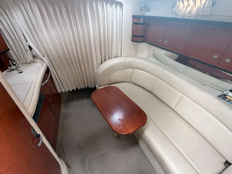 Slide: The Image of 2004 Sea Ray 300 Sundancer cabin with white leather seating and wooden table. - 18