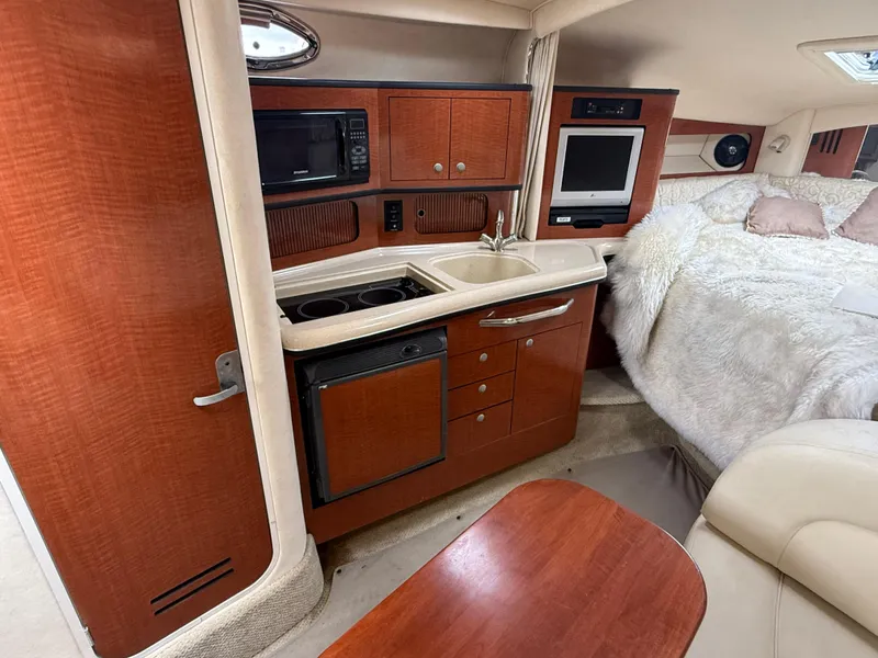 Slide: The Image of 2004 Sea Ray 300 Sundancer interior with kitchenette, microwave, sink, and cozy sleeping area. - 22