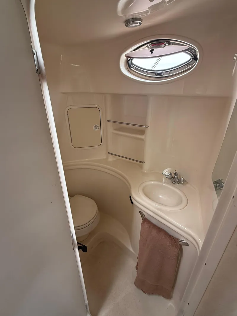 Slide: The Image of 2004 Sea Ray 300 Sundancer bathroom with sink, toilet, and porthole window. - 23