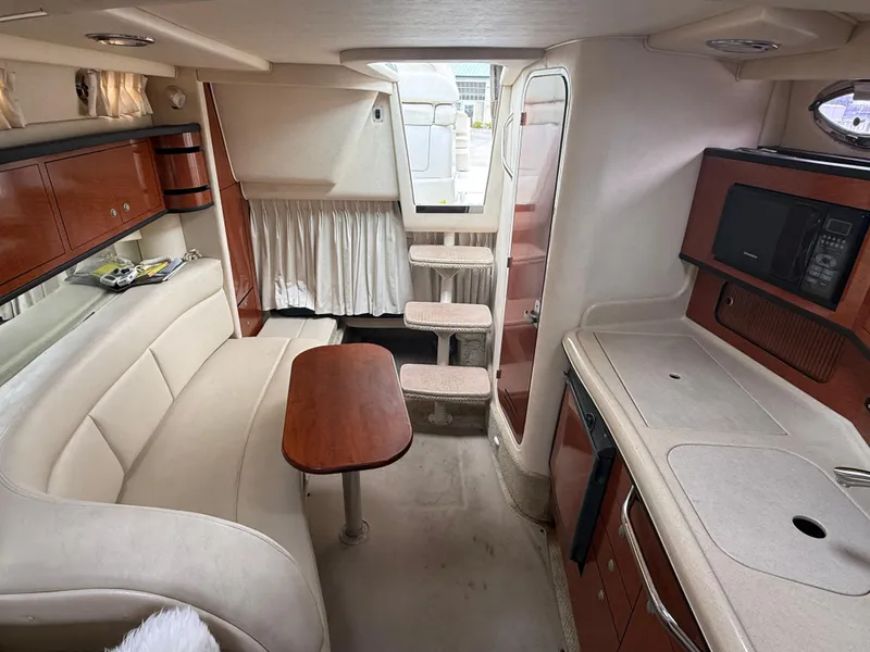 Slide: The Image of Interior of 2004 Sea Ray 300 Sundancer with seating, table, and kitchenette. - 25