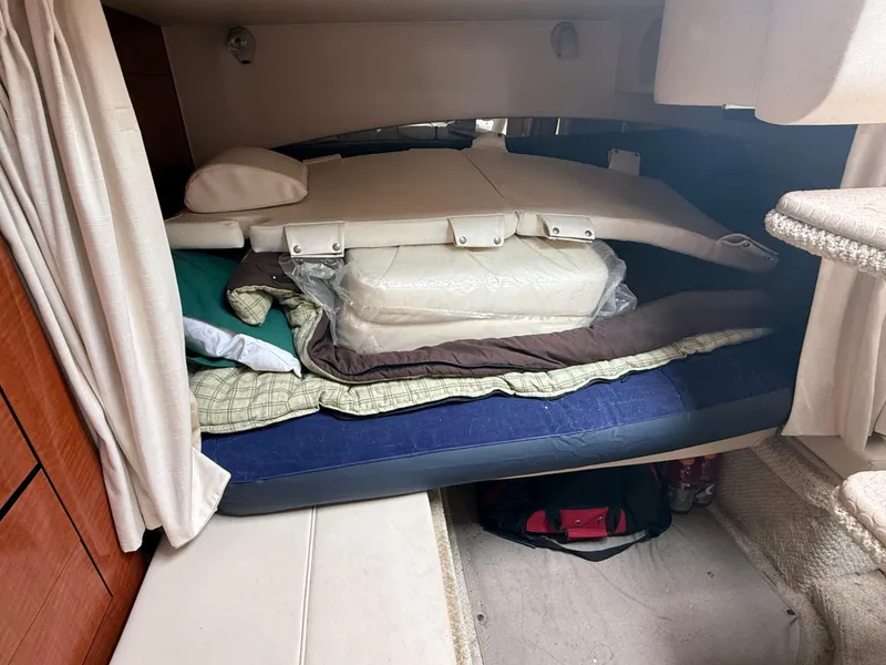 Slide: The Image of 2004 Sea Ray 300 Sundancer cabin with stacked bedding and cushions. - 26