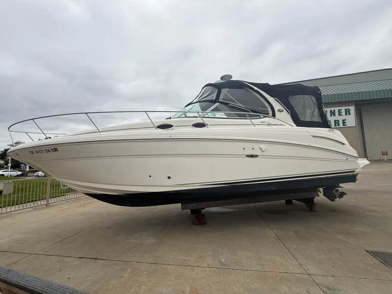 Slide: The Image of 2004 Sea Ray 300 Sundancer boat on display, white exterior, docked outdoors. - 3