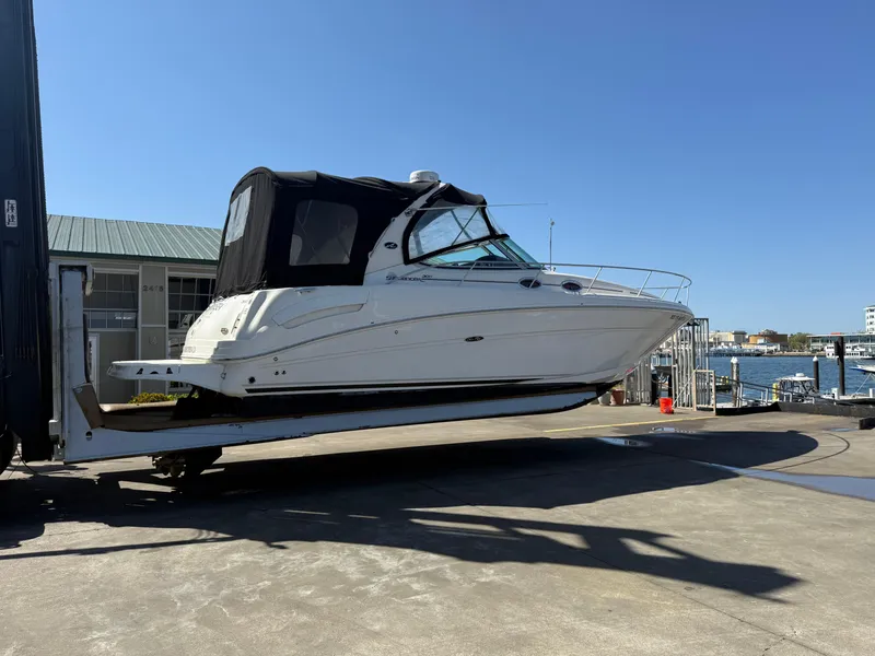 Slide: The Image of 2004 Sea Ray 300 Sundancer boat on a lift at a marina, clear sky background. - 6