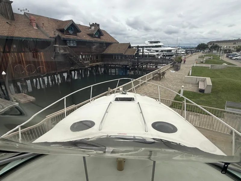 Slide: The Image of 2004 Sea Ray 300 Sundancer docked near rustic waterfront buildings and marina. - 8