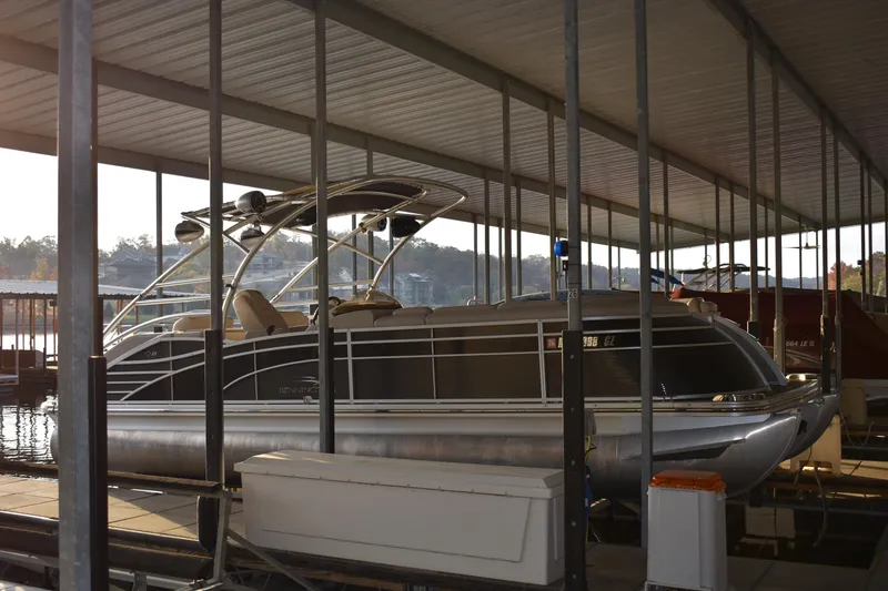 Slide: The Image of 2013 Bennington 2575 QCW I/O pontoon boat docked under a covered marina. - 1