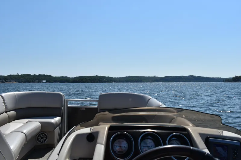 Slide: The Image of 2013 Bennington 2575 QCW I/O boat interior with lake view, clear sky, and plush seating. - 13