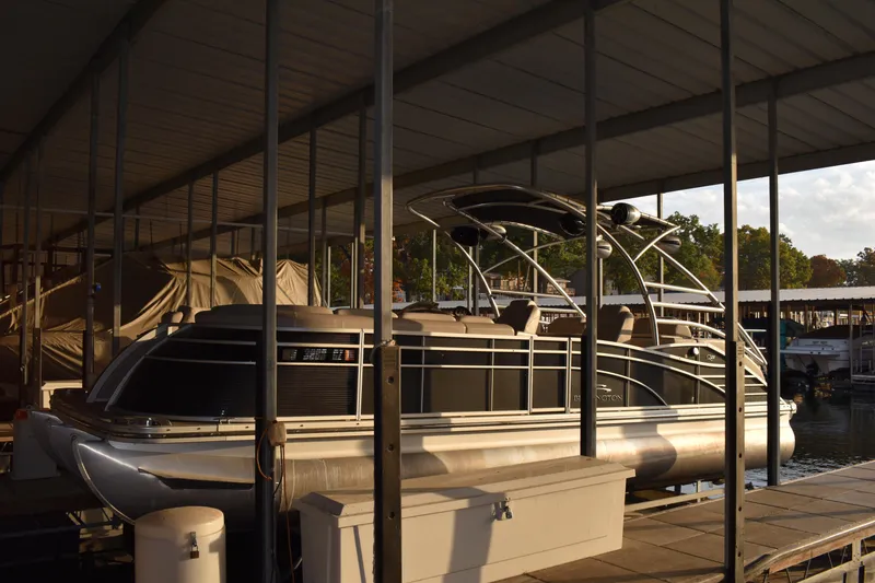 Slide: The Image of 2013 Bennington 2575 QCW I/O pontoon boat docked under a covered marina. - 2