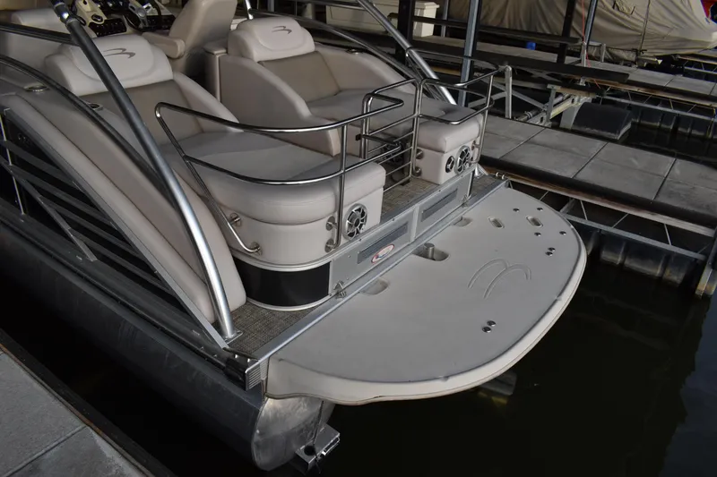 Slide: The Image of 2013 Bennington 2575 QCW I/O pontoon boat docked, featuring spacious seating and sleek design. - 3