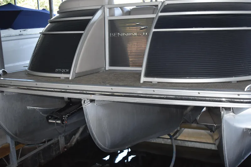 Slide: The Image of 2013 Bennington 2575 QCW I/O pontoon boat docked, showcasing sleek design and sturdy pontoons. - 37