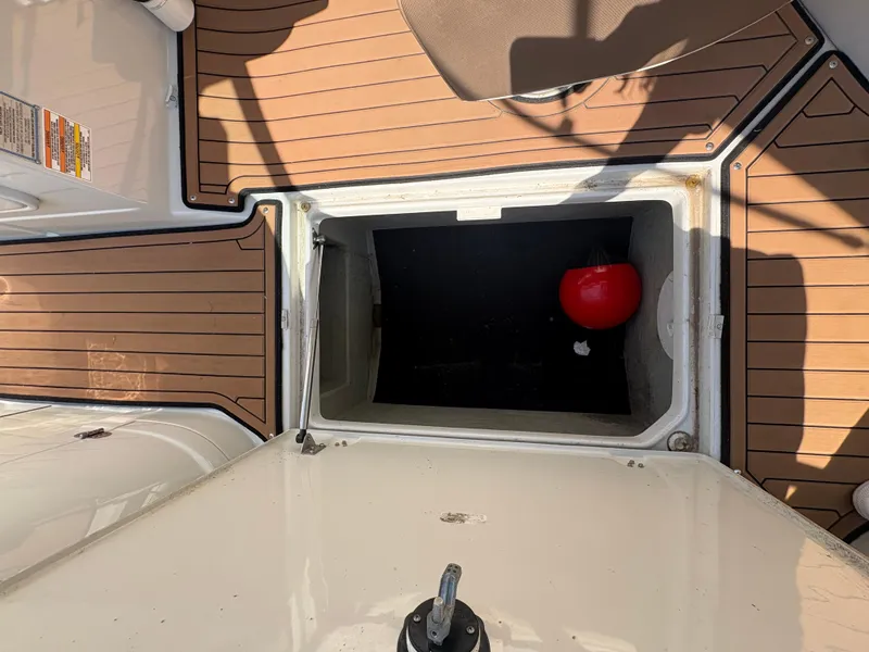 Slide: The Image of 2017 Crownline 285 SS boat storage compartment with red buoy on teak deck. - 29