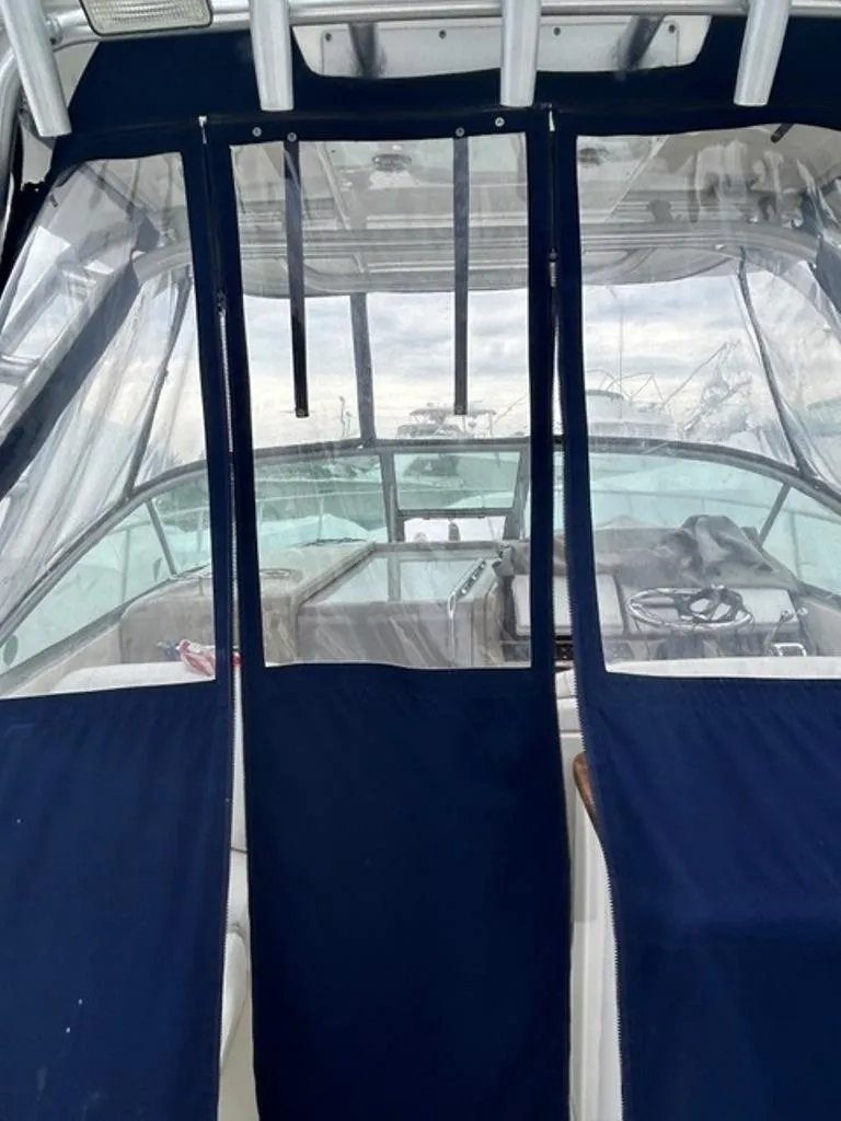 Slide: The Image of 2008 Sea Ray 290 Amberjack boat with blue canvas cover and clear windows. - 5