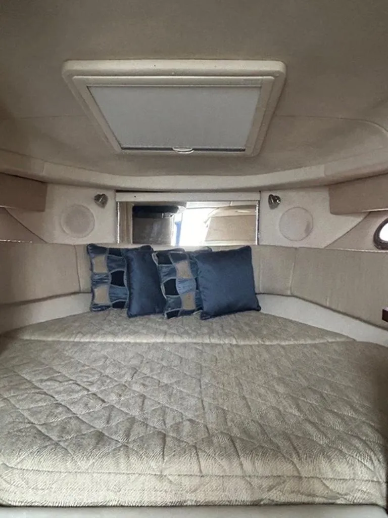 Slide: The Image of 2008 Sea Ray 290 Amberjack cabin interior with bed and blue pillows. - 7