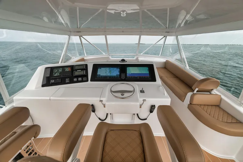 Slide: The Image of Helm of 2001 Viking 65 yacht with modern navigation displays and brown seating. - 13