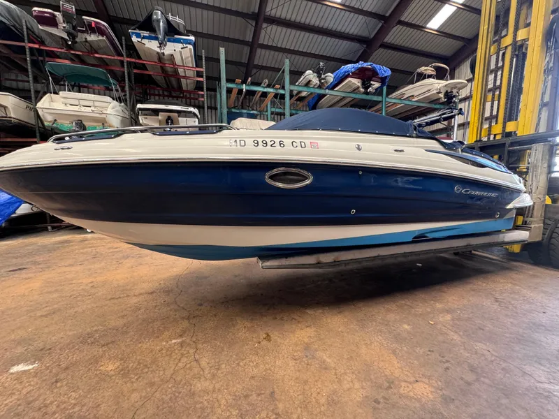 The Image of 2011 Crownline 245 SS boat in storage, blue and white hull, indoor facility. - 0