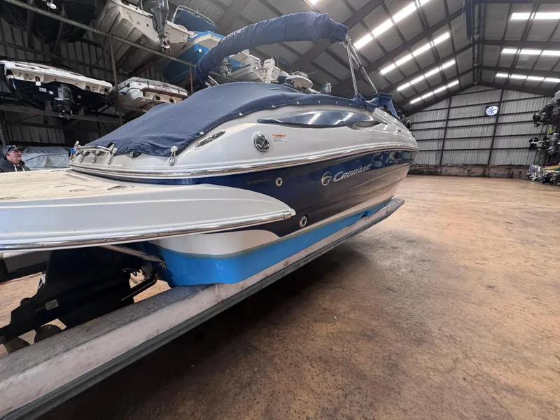 Slide: The Image of 2011 Crownline 245 SS boat in storage, blue and white exterior, covered, indoor facility. - 2
