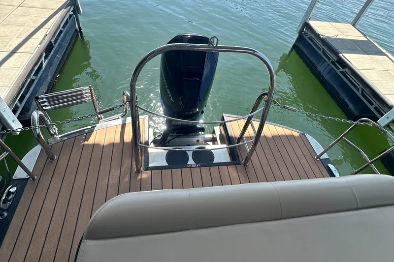 Slide: The Image of 2019 Harris Solstice 240 boat stern with motor, docked on calm water. - 24