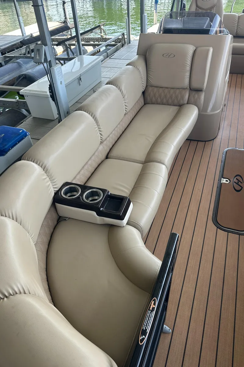 Slide: The Image of 2019 Harris Solstice 240 boat with beige leather seating and cup holders on deck. - 27