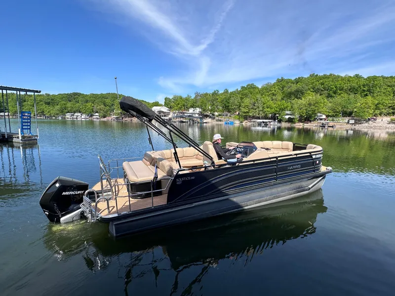 Slide: The Image of 2019 Harris Solstice 240 pontoon boat on a serene lake with lush green shoreline. - 3