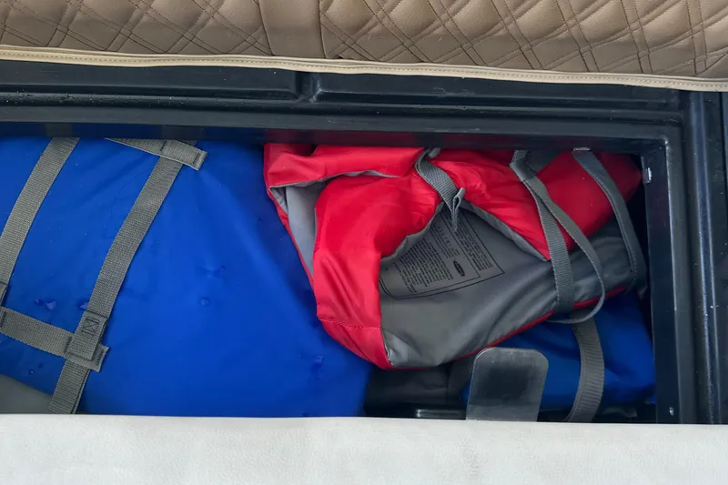 Slide: The Image of Storage compartment of 2019 Harris Solstice 240 with blue and red life jackets. - 32