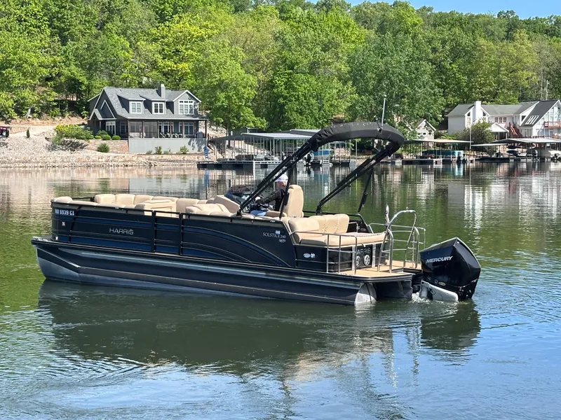 Slide: The Image of 2019 Harris Solstice 240 pontoon boat on a serene lake with lush greenery. - 4