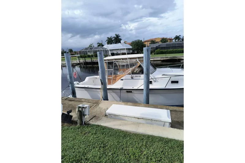 Slide: The Image of 1987 Luhrs Alura 30 boat docked by a canal under cloudy skies. - 3