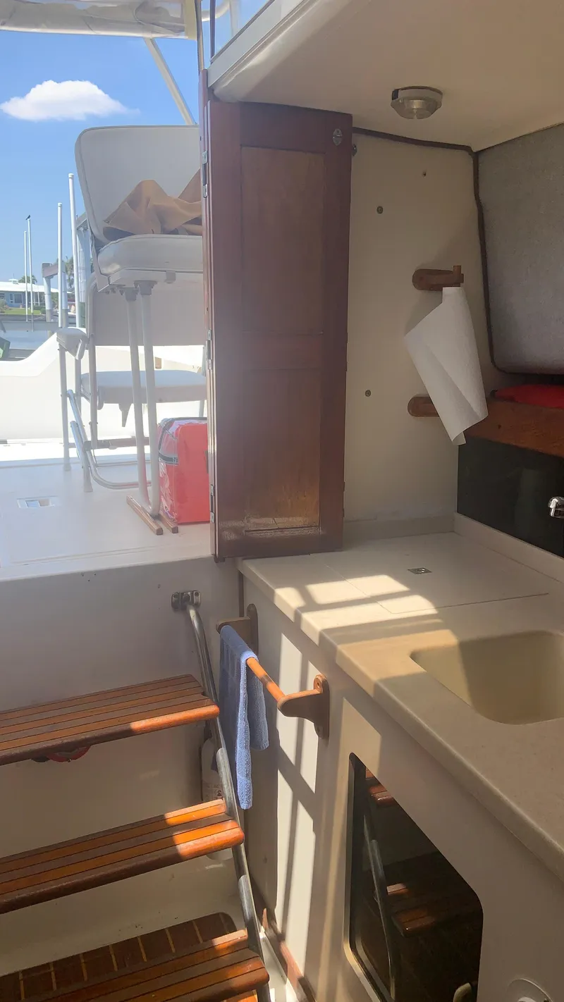 Slide: The Image of 1987 Luhrs Alura 30 boat interior with sink, wooden steps, and seating area. - 19