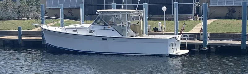Slide: The Image of 1987 Luhrs Alura 30 boat docked at a marina, side view. - 2