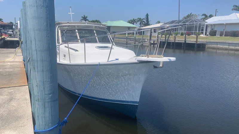 Slide: The Image of 1987 Luhrs Alura 30 boat docked in a marina, sunny day, calm water. - 3