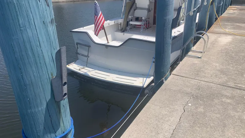 Slide: The Image of 1987 Luhrs Alura 30 boat docked, displaying an American flag, with blue mooring lines. - 5