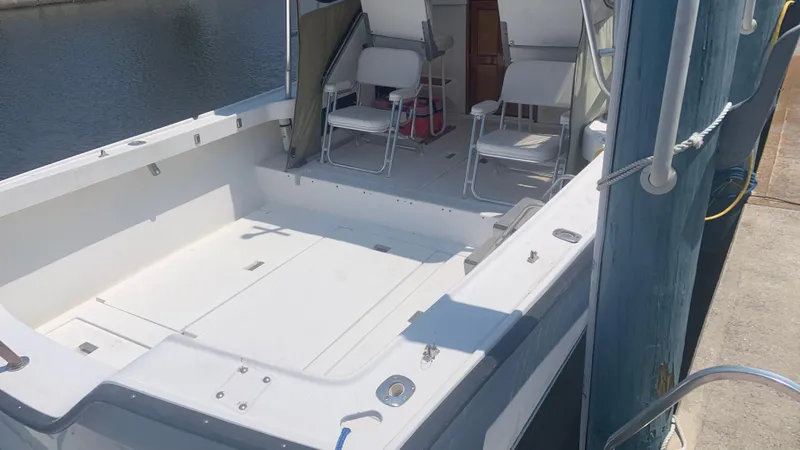 Slide: The Image of 1987 Luhrs Alura 30 boat docked, featuring spacious deck and seating area. - 6