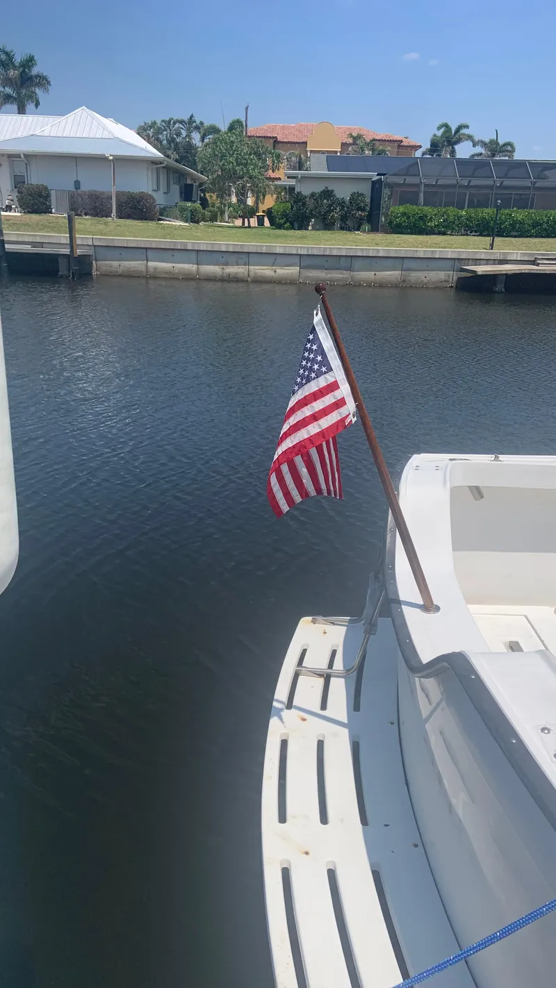 Slide: The Image of 1987 Luhrs Alura 30 boat with American flag docked in a canal. - 7