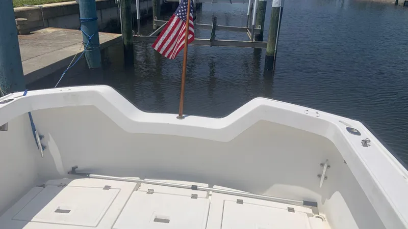 Slide: The Image of 1987 Luhrs Alura 30 boat stern with American flag, docked at marina. - 8