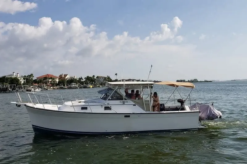 The Image of 1987 Luhrs Alura 30 boat cruising on a sunny day with passengers onboard. - 1