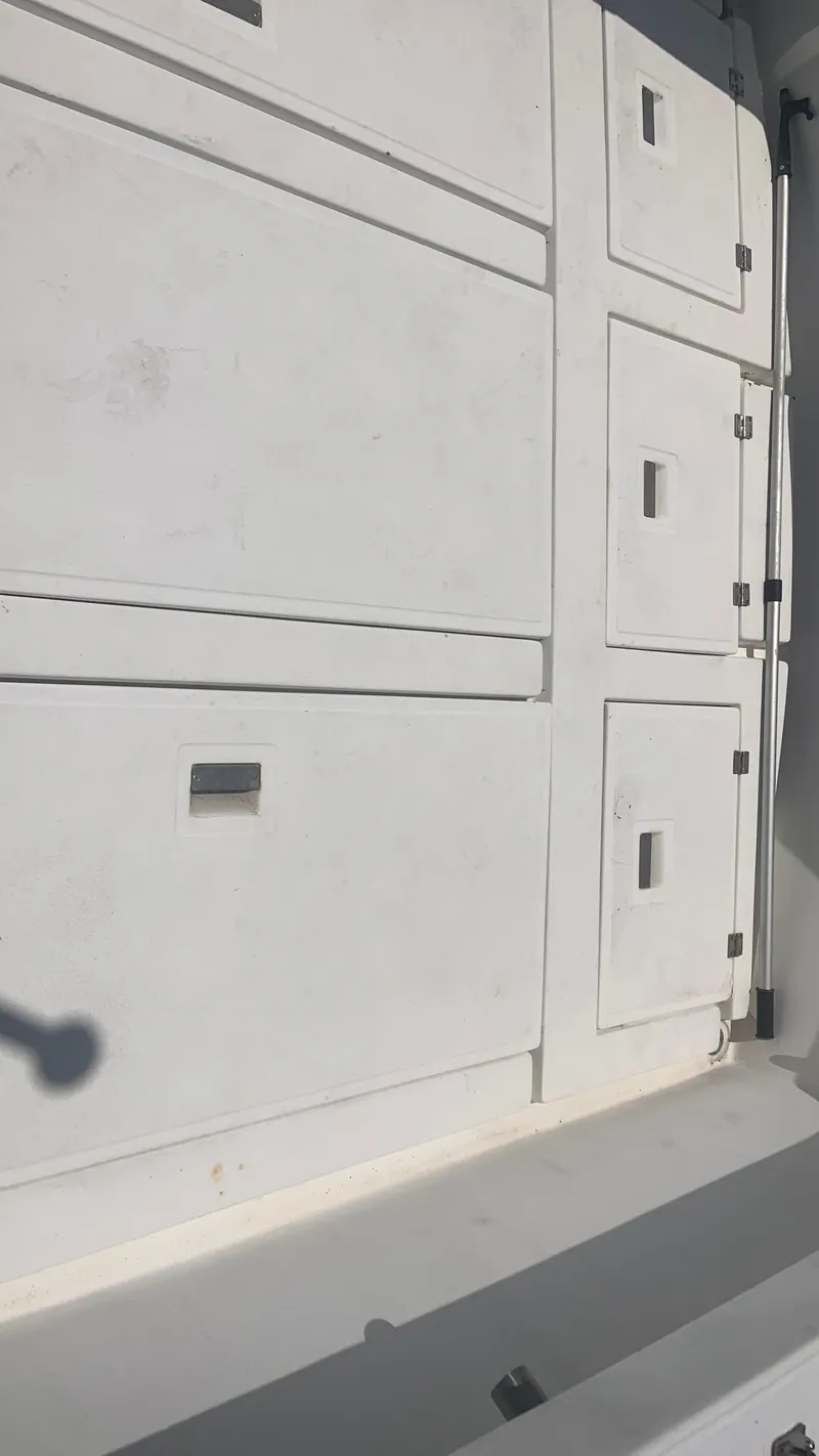 Slide: The Image of 1987 Luhrs Alura 30 boat storage compartments with white paneling and secure latches. - 9