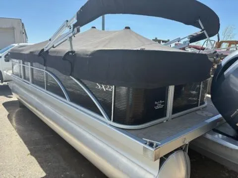 Slide: The Image of 2019 Bennington 22SLX pontoon boat with black cover and canopy, parked outdoors. - 3