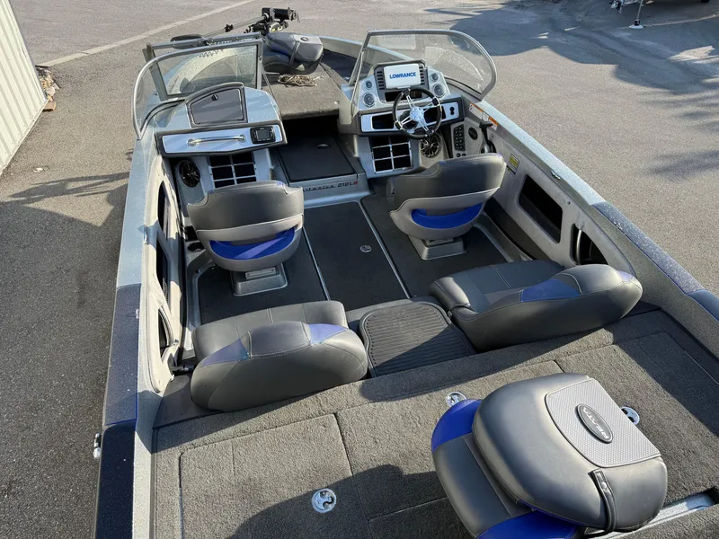 Slide: The Image of 2017 Ranger 212LS Reatta boat interior with seating and dashboard, parked on pavement. - 11
