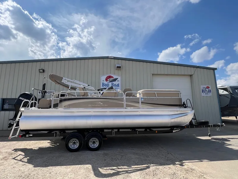 Slide: The Image of 2012 Bennington 24 SL pontoon boat on trailer, parked outside Boji Boat building. - 0