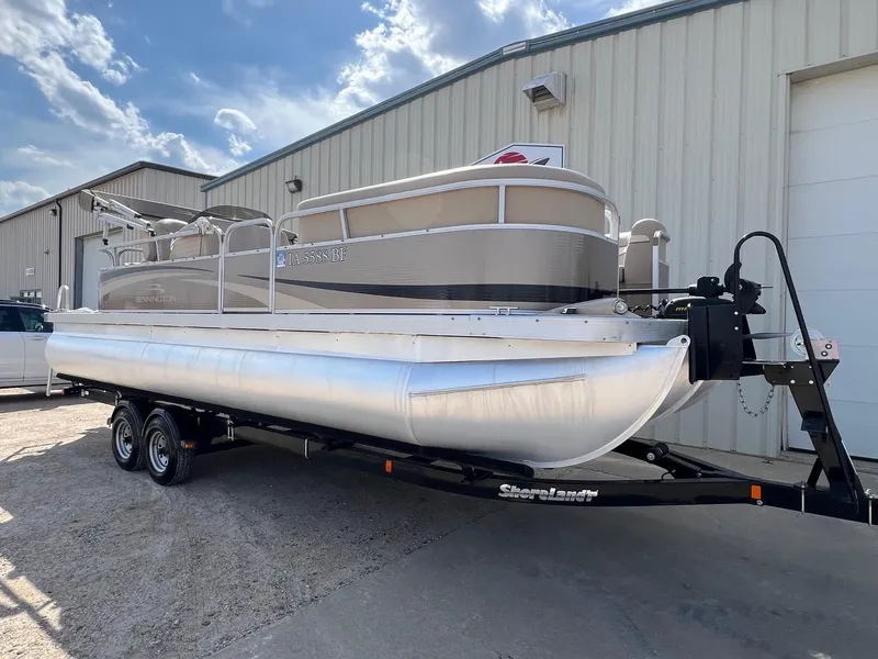 Slide: The Image of 2012 Bennington 24 SL pontoon boat on trailer, parked outside a warehouse. - 1