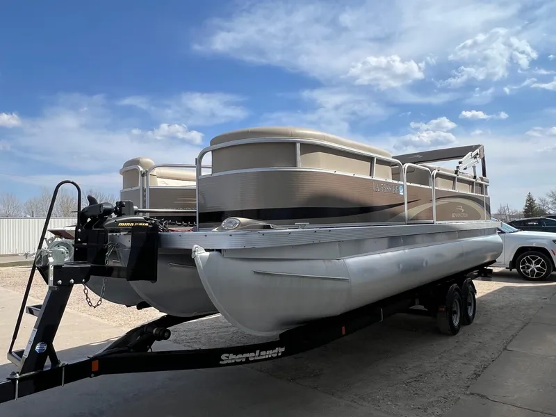 Slide: The Image of 2012 Bennington 24 SL pontoon boat on trailer under a clear blue sky. - 2