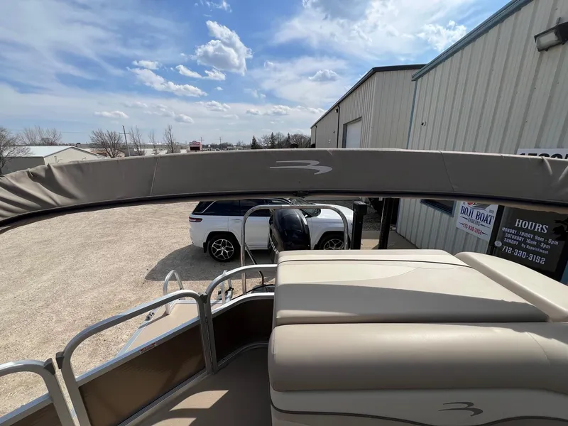 Slide: The Image of 2012 Bennington 24 SL pontoon boat parked near a building under a partly cloudy sky. - 20