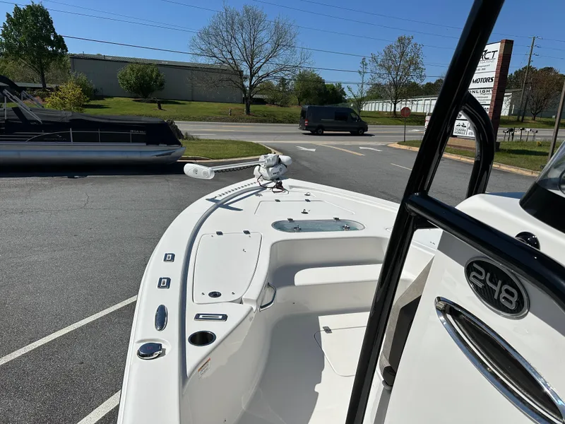 Slide: The Image of 2022 Sea Pro 248 DLX boat, white deck, parked outdoors on a sunny day. - 13
