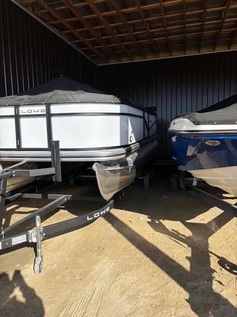 Slide: The Image of 2025 Lowe LS210 boats stored in a covered area, showcasing sleek design and durability. - 2